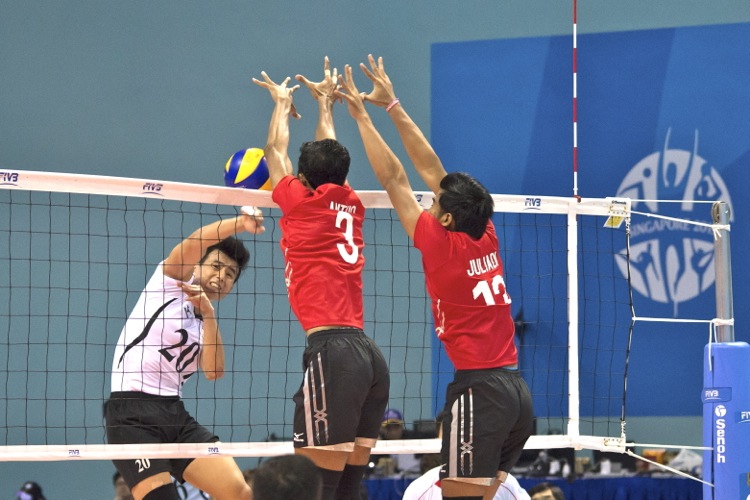 Melvin Goh (#20) is unsuccessful in getting the ball past the Indonesian center blockers at the net.