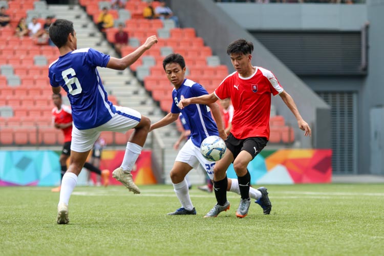 Javier Chua (NYJC #7) trying to get the ball out of his own half, under pressure from Kaung Htet Lu (TMJC #6) and Hameezan (TMJC #23). (Photo 2 © Clara Lau/REDintern)