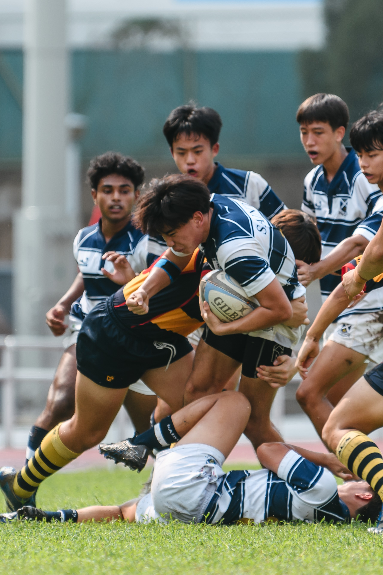 SAJC’s Joshua Quek (#11) gets caught in the tackle of ACS(I)’s Oscar McEwin (#26). (Photo 12 © Jared Chow/Red Sports)