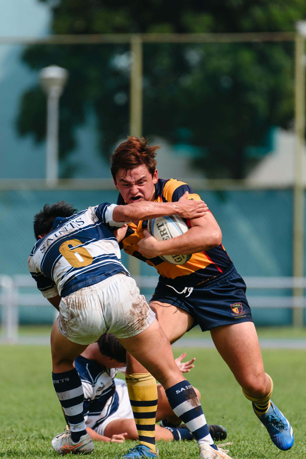 ACS(I)’s Oscar McEwin (#26) swats off an SAJC defender on his way to the try line. (Photo 7 © Jared Chow/Red Sports)