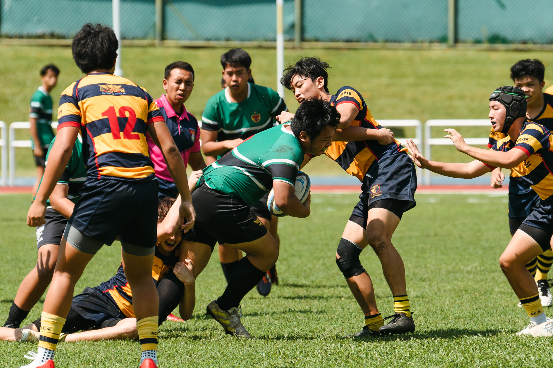 An RI player attempts to escape the tackles of two ACS(I) players. (Photo 5 © Joash Chow/Red Sports)